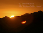 Sun Smile. Evergreen Mountain, Washington. The sun rises in the central Cascades. Interestingly, the partially risen sun reflects off of elements in the lens creating a lens flare which looks eerily like smiling lips. � Ben Babusis, Lightscape Gallery.
